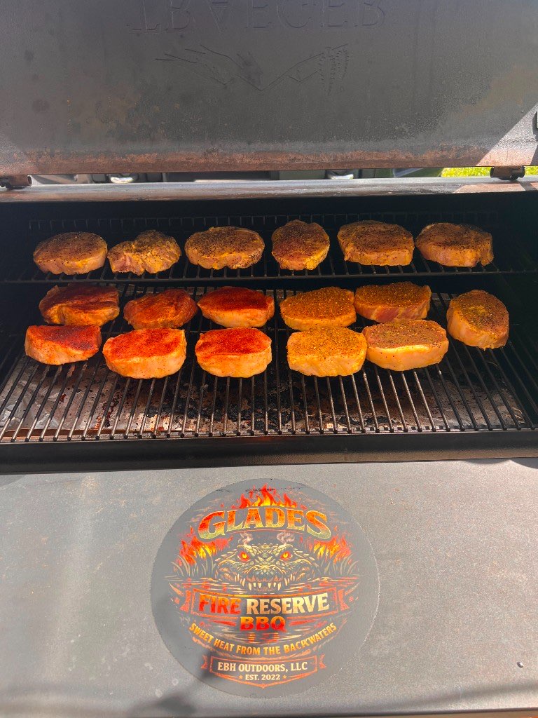 Two rows of seasoned pork chops on the grates of the pellet grill