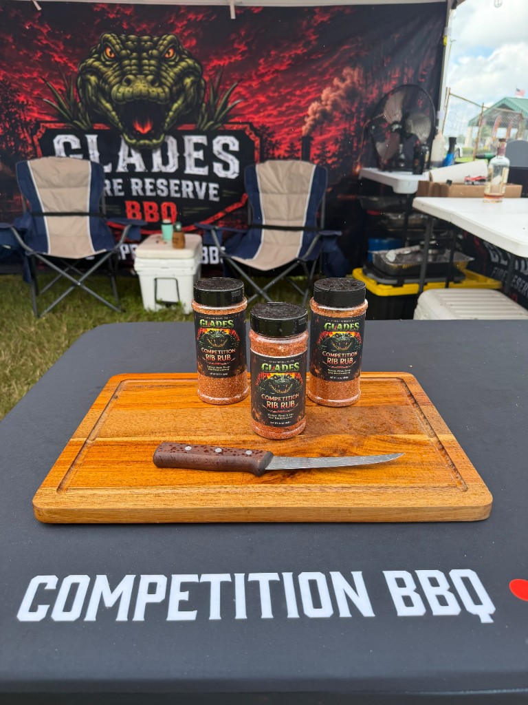 Three shakers of Glades Competition Rib Rub and a boning knife on a board atop the Competition BBQ table