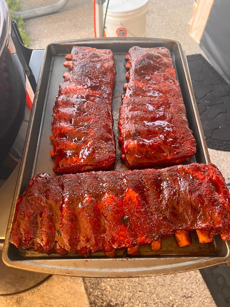 Three lacquered racks of ribs resting on a sheet pan