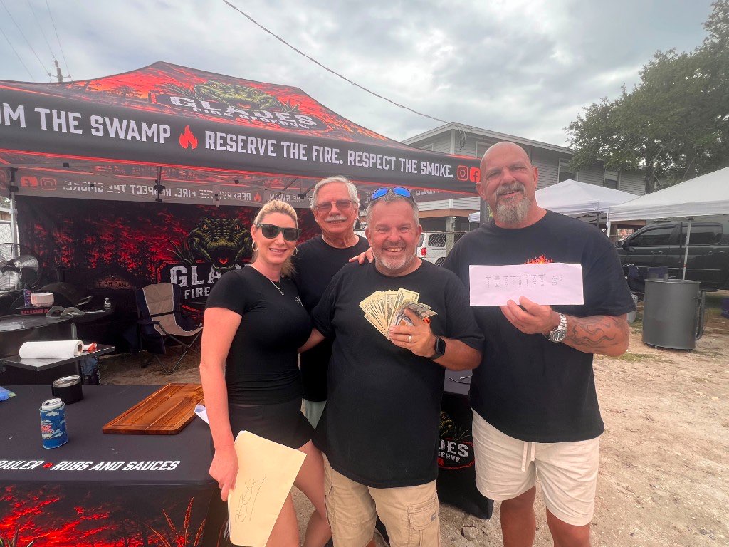 Four team members outside the tent holding prize money and a winner's envelope